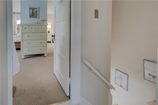 corridor with light colored carpet and an upstairs landing
