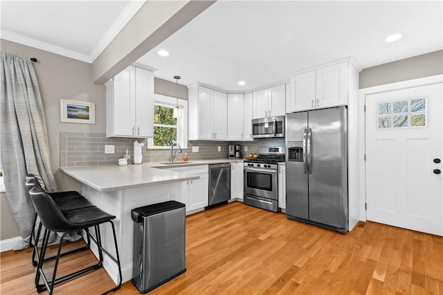 120 Columbia Heights Rd Unit 1, Charlestown, RI 02813 - kitchen with crown molding, appliances with stainless steel finishes, a sink, light countertops, and a peninsula