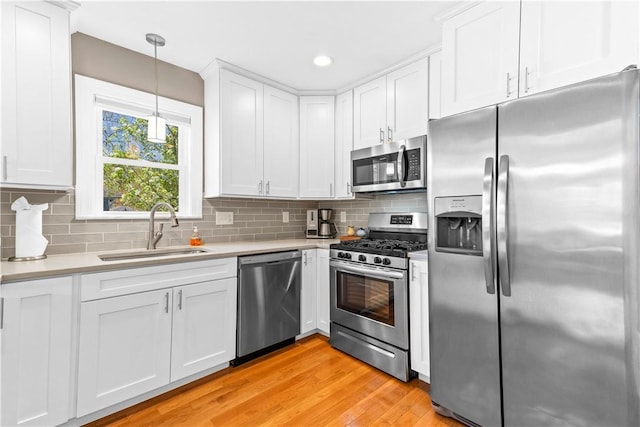 120 Columbia Heights Rd Unit 1, Charlestown, RI 02813 - kitchen with light wood-type flooring, light countertops, white cabinetry, a sink, and stainless steel appliances