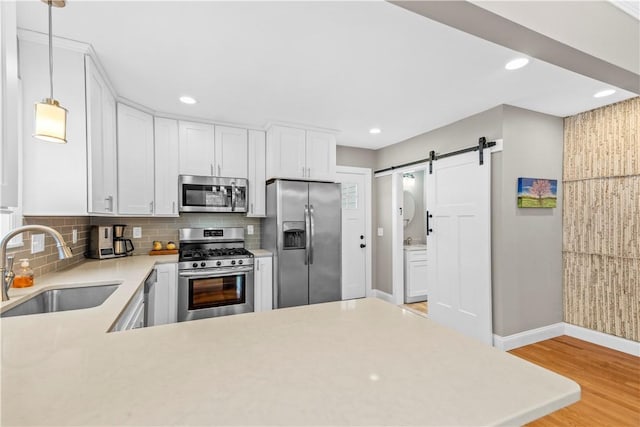 120 Columbia Heights Rd Unit 1, Charlestown, RI 02813 - kitchen featuring appliances with stainless steel finishes, a barn door, a sink, light countertops, and light wood-style floors