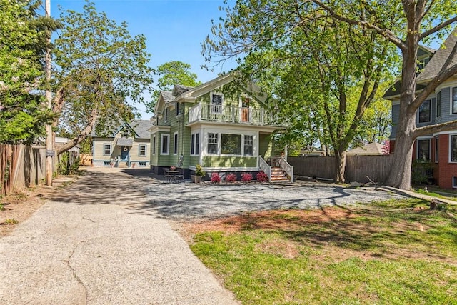 rear view of house with aphalt driveway, fence, and a balcony