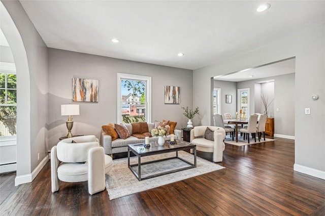 living area with baseboards, recessed lighting, dark wood-style flooring, and arched walkways