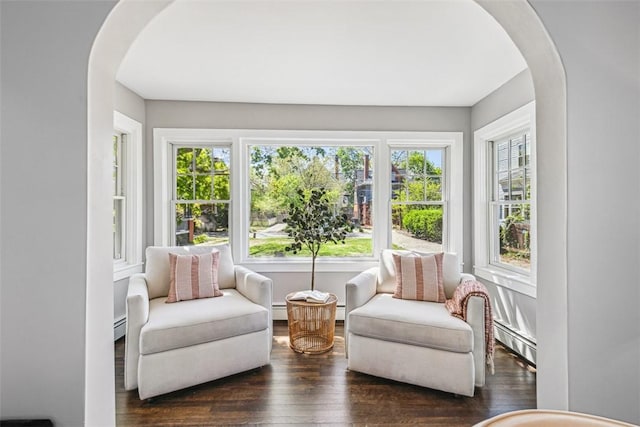 sunroom / solarium featuring a healthy amount of sunlight, arched walkways, and a baseboard heating unit