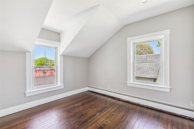 additional living space featuring dark wood-style floors, lofted ceiling, baseboard heating, and a healthy amount of sunlight