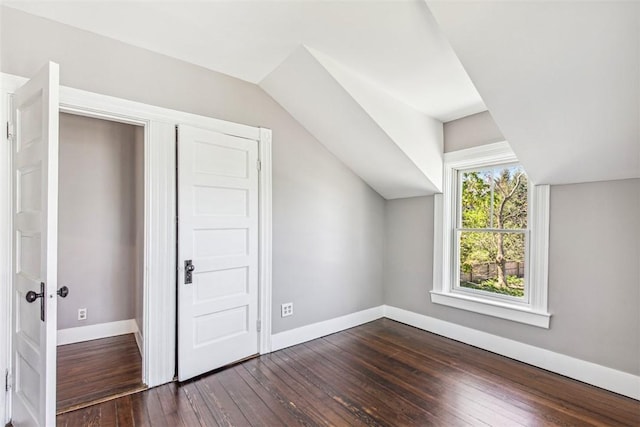 bonus room with baseboards, vaulted ceiling, and dark wood-type flooring