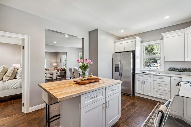 kitchen featuring dark wood-style flooring, stainless steel refrigerator with ice dispenser, white cabinetry, and a kitchen bar