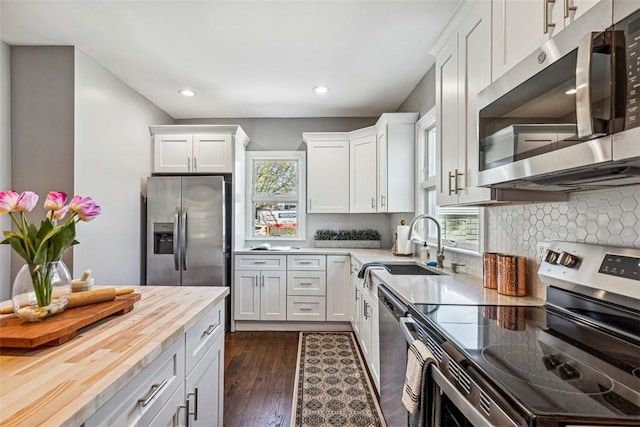 kitchen with wooden counters, recessed lighting, white cabinets, a sink, and appliances with stainless steel finishes