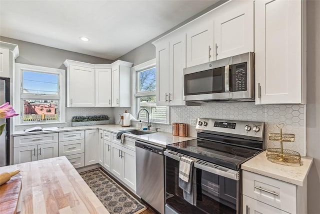 kitchen with a sink, decorative backsplash, appliances with stainless steel finishes, and white cabinets