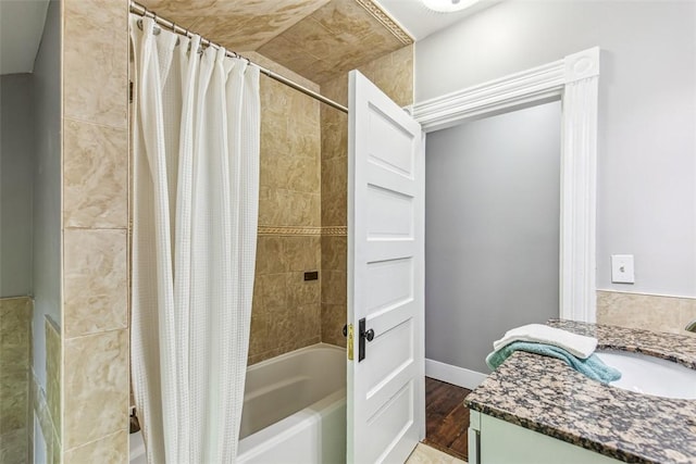 bathroom featuring vanity, baseboards, shower / bathtub combination with curtain, and wood finished floors