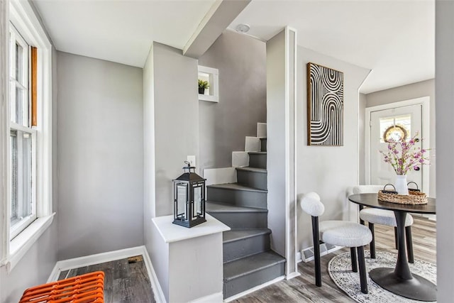 staircase featuring baseboards, wood finished floors, and a wealth of natural light