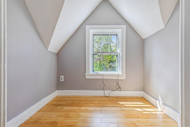 additional living space featuring baseboards, vaulted ceiling, and light wood-type flooring