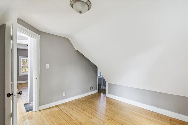 additional living space featuring baseboards, lofted ceiling, visible vents, and wood finished floors