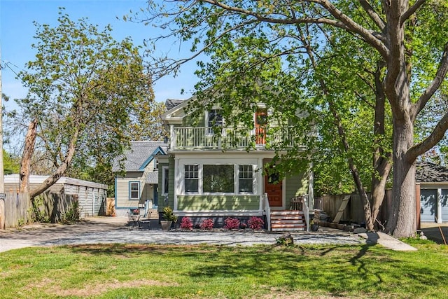 view of front of house with fence, a balcony, and a front yard