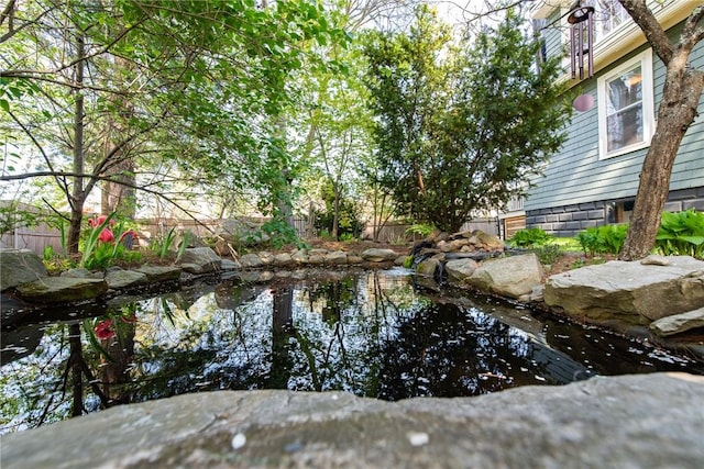 exterior space featuring fence and a small pond