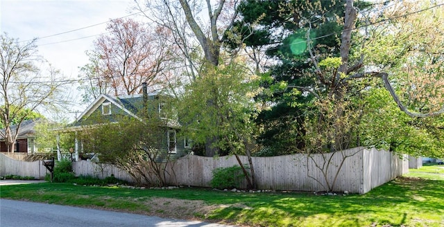 view of property exterior featuring fence and a lawn
