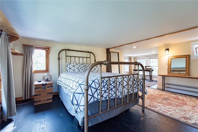 bedroom featuring a baseboard radiator, multiple windows, recessed lighting, and wood finished floors