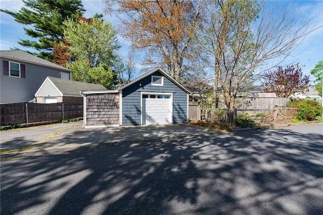 detached garage featuring fence and driveway