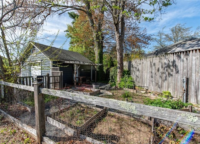 view of yard with fence, an outbuilding, and a vegetable garden