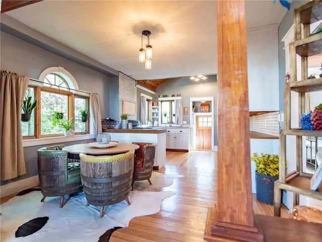 dining area featuring decorative columns, lofted ceiling, and light wood-type flooring
