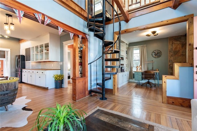 living room with stairs, a high ceiling, and light wood-style floors
