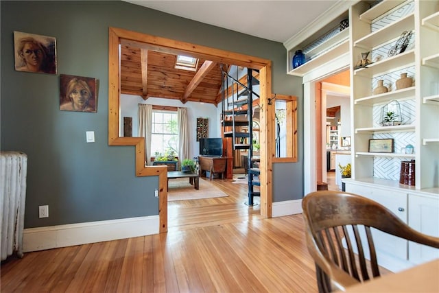 interior space featuring vaulted ceiling with skylight, wood ceiling, wood finished floors, baseboards, and radiator heating unit
