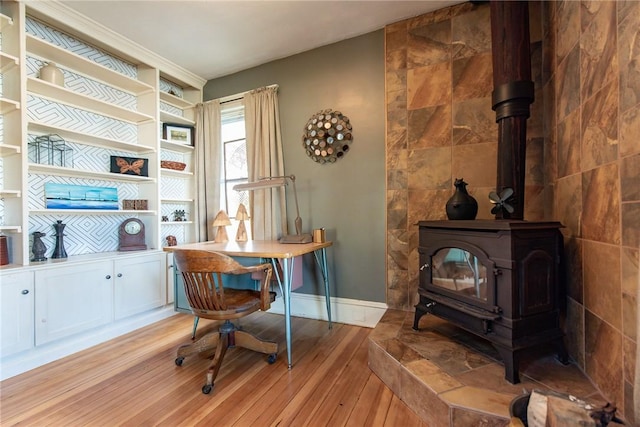 office space featuring baseboards, light wood-style flooring, and a wood stove