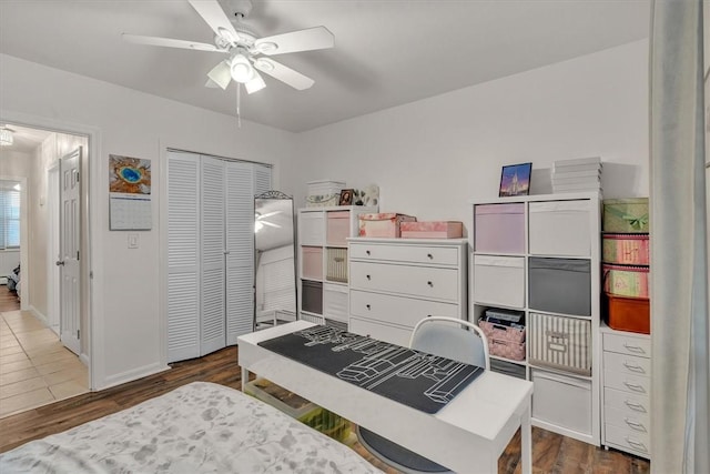 bedroom featuring baseboards, ceiling fan, wood finished floors, and a closet