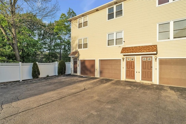 view of side of property with an attached garage, fence, and driveway