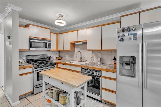 kitchen featuring ornamental molding, a sink, backsplash, light tile patterned floors, and stainless steel appliances