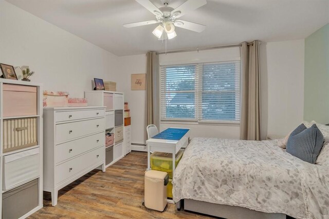 bedroom with baseboard heating, a ceiling fan, and light wood-type flooring