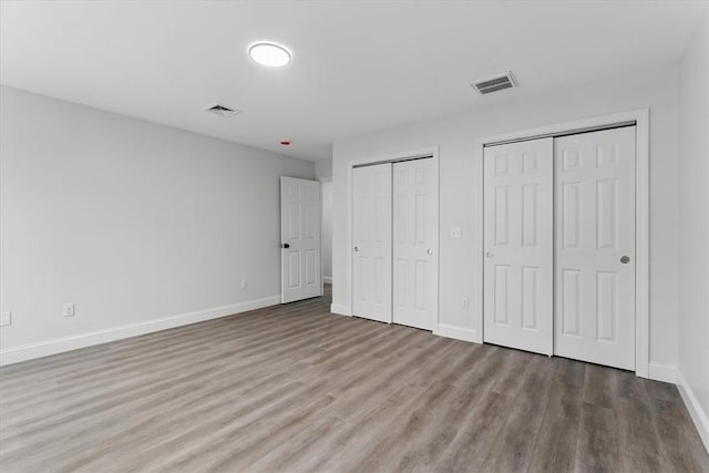 87 Dunedin St, Cranston, RI 02920 - unfurnished bedroom with two closets, baseboards, visible vents, and wood finished floors