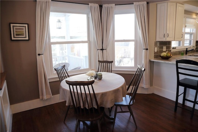 dining space featuring baseboards, a wealth of natural light, and dark wood-type flooring