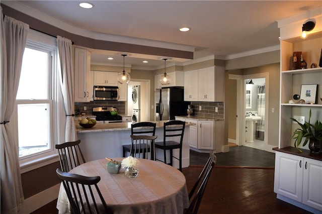 dining space featuring recessed lighting, stacked washer / drying machine, dark wood-style flooring, and a wealth of natural light