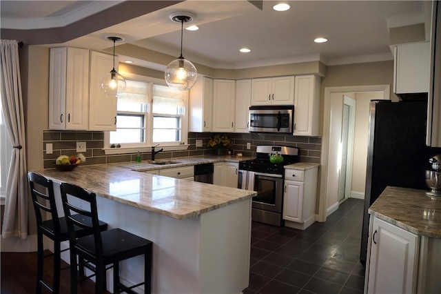 kitchen with decorative backsplash, white cabinets, stainless steel appliances, and a peninsula