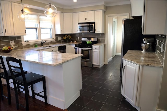 kitchen with a sink, stainless steel appliances, a peninsula, and white cabinetry