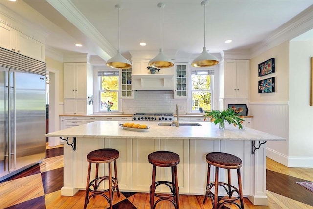 kitchen featuring a sink, backsplash, white cabinets, and stainless steel built in refrigerator