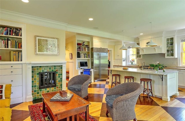 living room featuring recessed lighting, ornamental molding, a tiled fireplace, and light wood-style floors