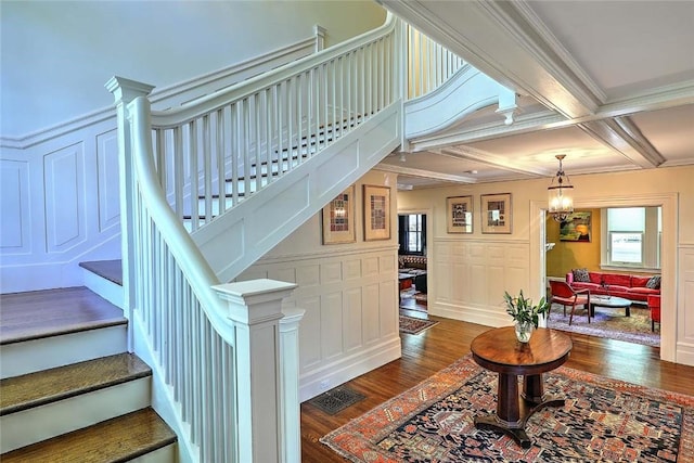 stairs featuring beamed ceiling, a decorative wall, wood finished floors, and visible vents