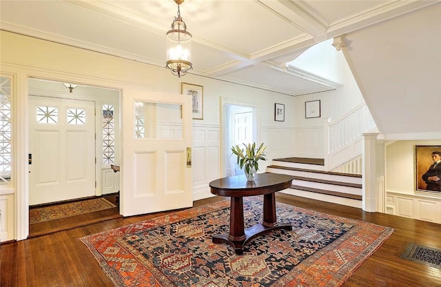 foyer entrance featuring wood finished floors, beam ceiling, a decorative wall, stairway, and a wainscoted wall