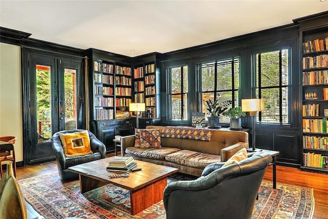living area with crown molding, built in features, plenty of natural light, and wood finished floors