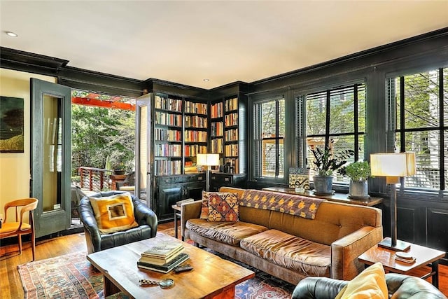 living area with crown molding, plenty of natural light, and wood-type flooring