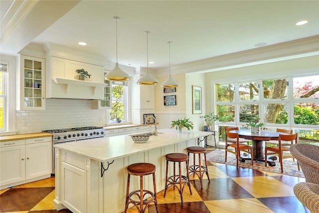 kitchen featuring crown molding, decorative backsplash, a kitchen bar, and stainless steel stove