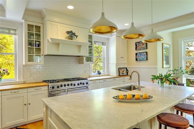 kitchen featuring a sink, white cabinets, a breakfast bar area, and range with two ovens