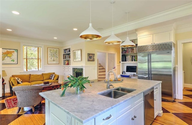 kitchen featuring appliances with stainless steel finishes, ornamental molding, a sink, and light wood finished floors