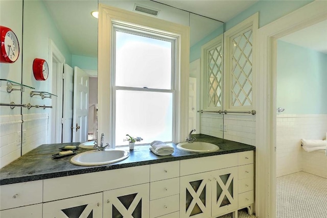 bathroom with a sink, backsplash, double vanity, and visible vents