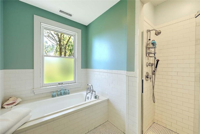 bathroom featuring visible vents, a bath, a stall shower, and a wealth of natural light
