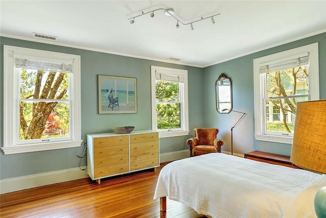 bedroom featuring visible vents, baseboards, multiple windows, and hardwood / wood-style floors