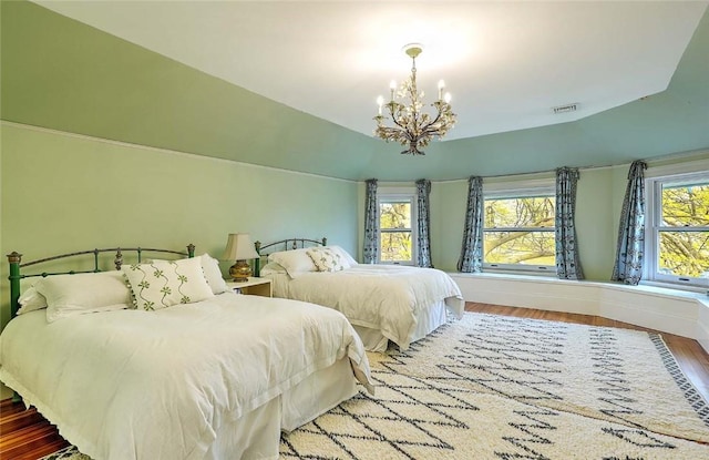 bedroom featuring baseboards, an inviting chandelier, wood finished floors, and visible vents