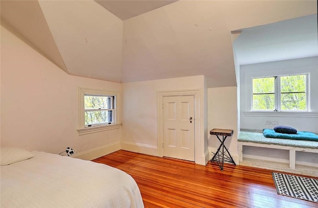 bedroom featuring baseboards, vaulted ceiling, multiple windows, and wood finished floors