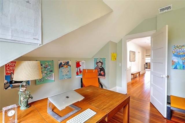 home office featuring visible vents, wood finished floors, and vaulted ceiling